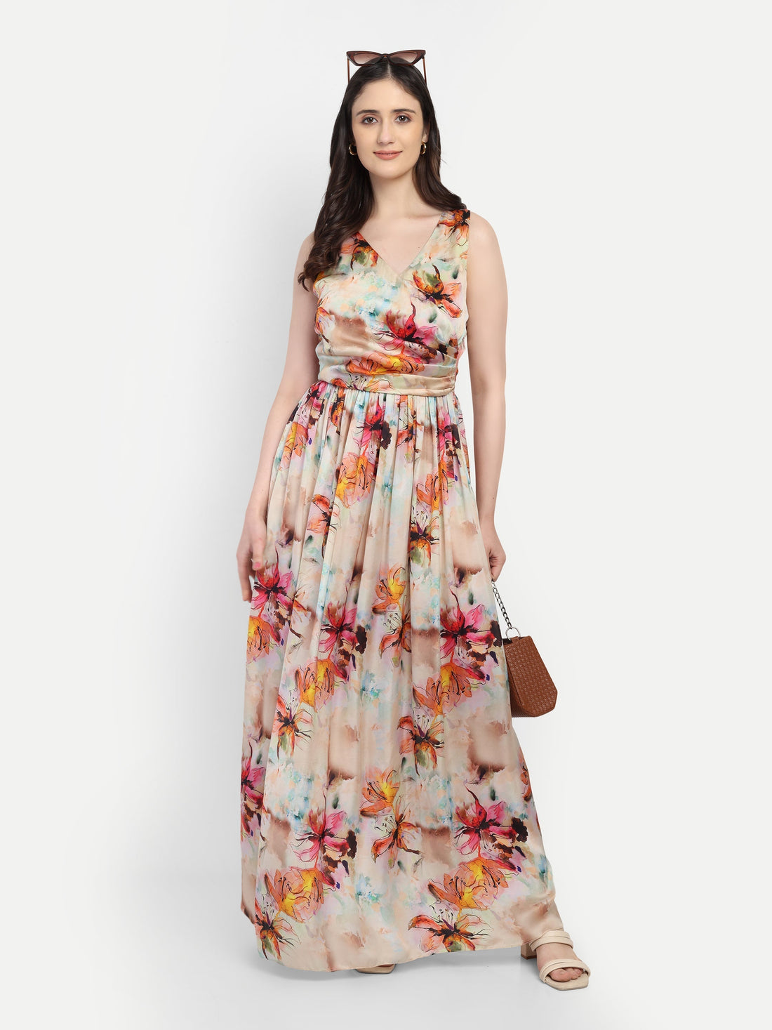 "Model wearing Trendland sleeveless floral print maxi gown in premium modal satin with a V-neckline and pleated waist, styled with a small brown handbag."
